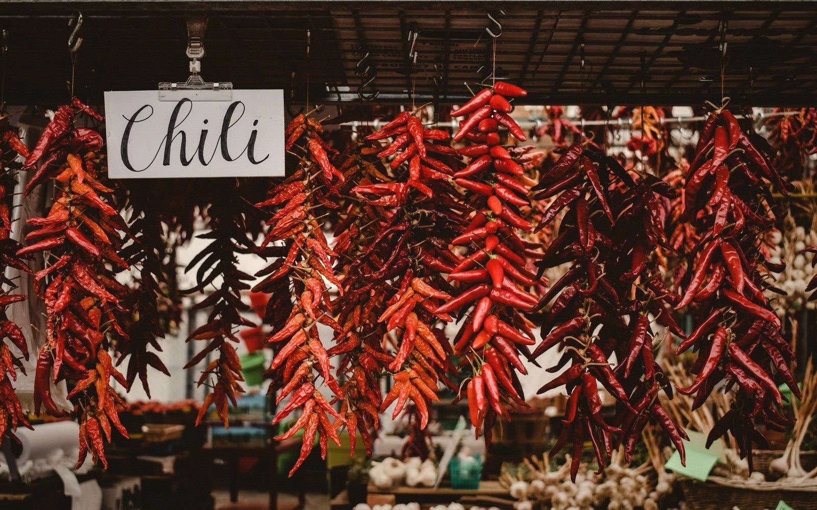 Market stall of dried chillies in multiple colours, loose and in bundles